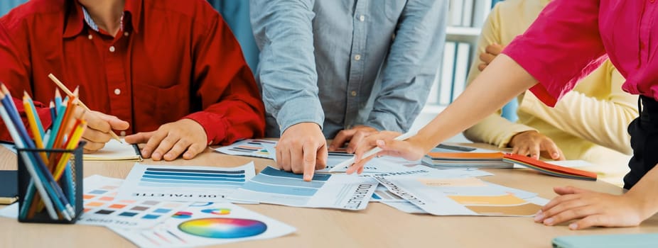 A cropped image of professional interior designer discuss the color material with her colleagues by comparing with color swatches and color palette document. Creative design concept. Variegated.