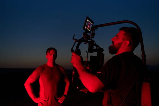 A skilled videographer captures the intensity of athletes running, illuminated by vibrant red lights, encapsulating the energy and determination of their nighttime training session.