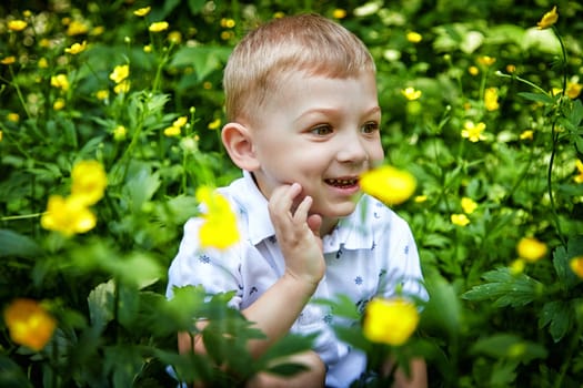 A smiling boy with a distinctive haircut enjoys nature surrounded by vibrant yellow blooms. The concept of a happy childhood and ecology