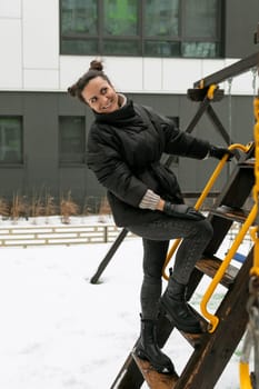 Young pretty woman in a winter jacket fooling around on the playground.