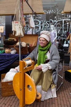 Brielle,Holland,1-04-2024:a woman in traditional costume is spinning on a spinning wheel during the celebration of the the first town to be liberated from the Spanish in Den Briel in the Netherlands