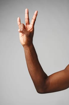 A mans arm is extended, with his hand forming a peace sign gesture.