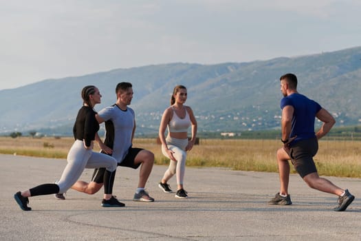 A determined group of athletes engage in a collective stretching session before their run, fostering teamwork and preparation in pursuit of their fitness goals.