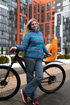 European woman with blond hair rides a bicycle in an urban environment.