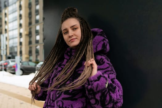 Beautiful young woman in an informal look with dreadlocks against the background of the street.