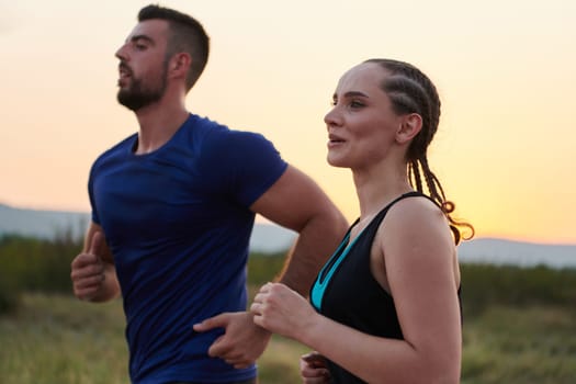 A vibrant couple dashes running the outdoors, embodying the essence of athleticism and romance, their confident strides reflecting a shared commitment to fitness and preparation for future marathon challenges.