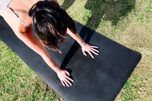 top view of an unrecognizable woman doing yoga stretching exercises in the grass of the park, active and healthy lifestyle concept