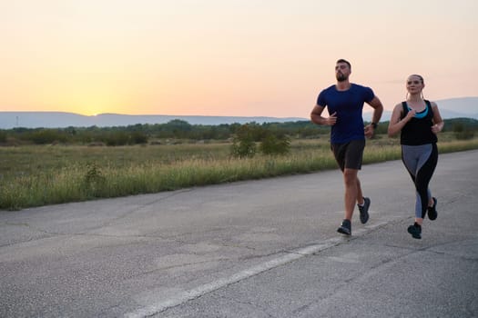 A vibrant couple dashes running the outdoors, embodying the essence of athleticism and romance, their confident strides reflecting a shared commitment to fitness and preparation for future marathon challenges.