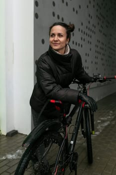 Lifestyle concept, young brunette woman standing at the entrance with a bicycle.
