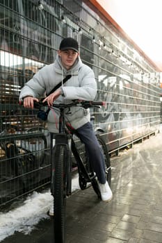 Bike rental concept. A man walks through the city in winter with a bicycle.