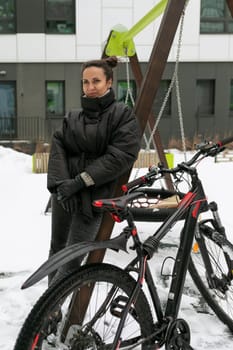 Young pretty woman in a winter jacket riding a bicycle.