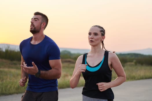 A vibrant couple dashes running the outdoors, embodying the essence of athleticism and romance, their confident strides reflecting a shared commitment to fitness and preparation for future marathon challenges.