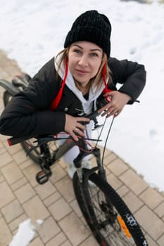 Young woman in winter clothes riding a bicycle.