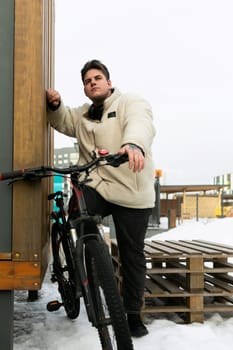 A young European man stopped while cycling near the wall of a house.