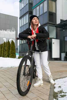 A woman took a rented bicycle with her while walking along a city street in winter.