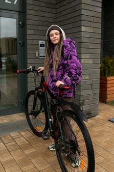 Lifestyle concept. Young woman walking with a bicycle in an urban environment.