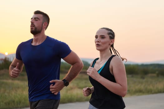 A vibrant couple dashes running the outdoors, embodying the essence of athleticism and romance, their confident strides reflecting a shared commitment to fitness and preparation for future marathon challenges.