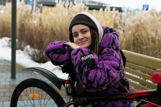 European stylish woman in an informal look rides a bicycle on the street.