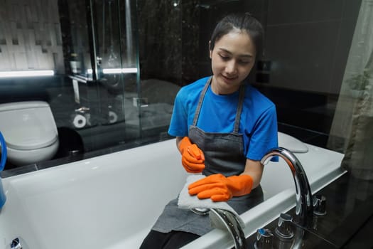 Cleaning online service. yong woman housekeeper cleaning bathtub in bathroom with a cloth. House cleaning service concept.