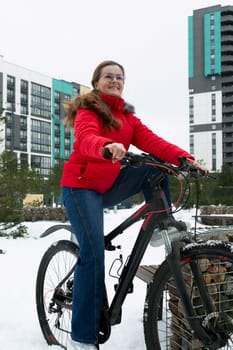 Active European woman pedaling a bicycle in winter.