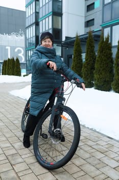 Elderly woman doing sports and riding a bicycle on the street.