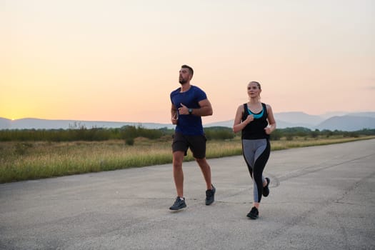 A vibrant couple dashes running the outdoors, embodying the essence of athleticism and romance, their confident strides reflecting a shared commitment to fitness and preparation for future marathon challenges.