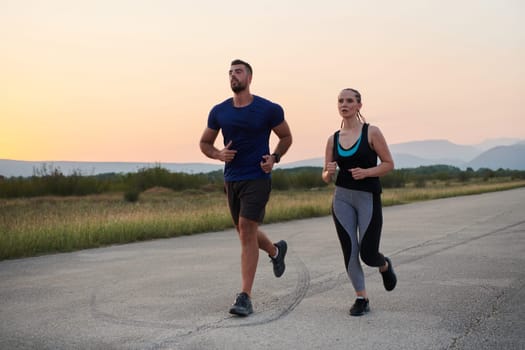 A vibrant couple dashes running the outdoors, embodying the essence of athleticism and romance, their confident strides reflecting a shared commitment to fitness and preparation for future marathon challenges.