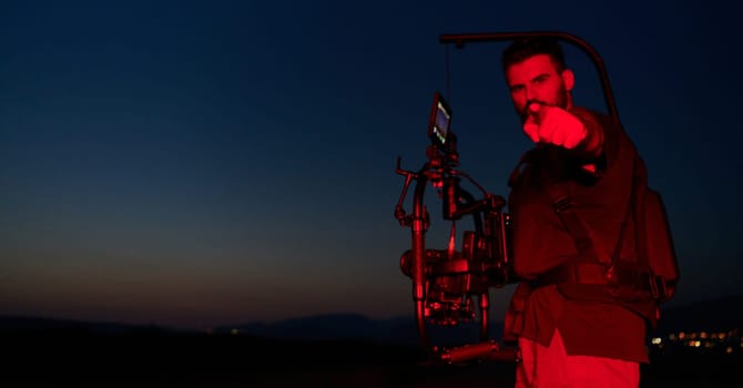 A skilled videographer captures the intensity of athletes running, illuminated by vibrant red lights, encapsulating the energy and determination of their nighttime training session.