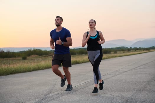 A vibrant couple dashes running the outdoors, embodying the essence of athleticism and romance, their confident strides reflecting a shared commitment to fitness and preparation for future marathon challenges.