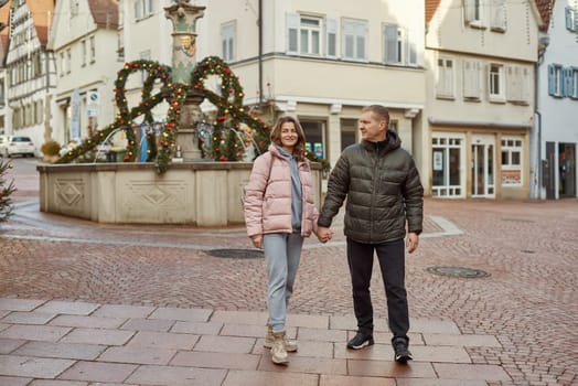 Loving couple of tourists walking around old town. Man woman couple walking europe old town Germany. Couple of lovers leisurely stroll in the cool autumn morning on the streets of a BIETIGHEIM-BISSINGEN (Germany). The guy holds his wife. Vacation, autumn, holiday. Couple Walking in Europe's Old Town