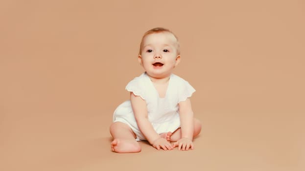 Portrait of happy cute baby crawling on the floor on brown studio background
