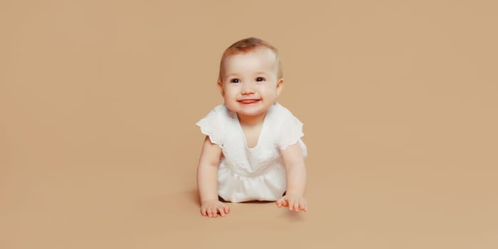 Portrait of happy cute baby crawling on the floor on brown studio background