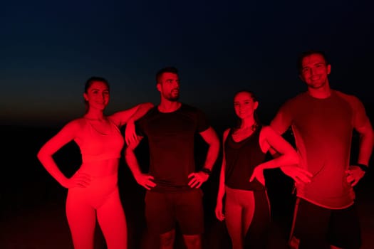 In the late-night hours, a diverse group of exhausted athletes find solace under a red glow, reflecting on their day-long marathon journey and celebrating camaraderie amidst fatigue.