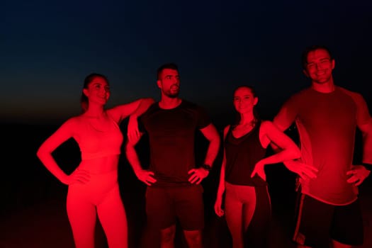 In the late-night hours, a diverse group of exhausted athletes find solace under a red glow, reflecting on their day-long marathon journey and celebrating camaraderie amidst fatigue.