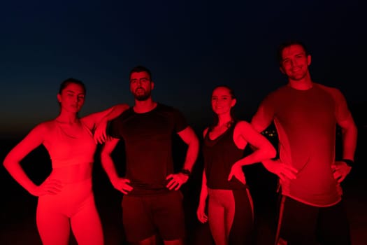 In the late-night hours, a diverse group of exhausted athletes find solace under a red glow, reflecting on their day-long marathon journey and celebrating camaraderie amidst fatigue.