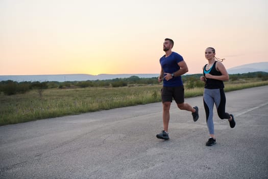 A vibrant couple dashes running the outdoors, embodying the essence of athleticism and romance, their confident strides reflecting a shared commitment to fitness and preparation for future marathon challenges.