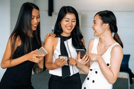 Three women friends having conversation while looking at mobile phone in their hands. Concept of social media, gossip news and online shopping. uds