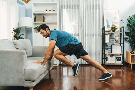 Athletic body and active sporty man using furniture for effective targeting muscle gain exercise at gaiety home exercise as concept of healthy fit body home workout lifestyle.