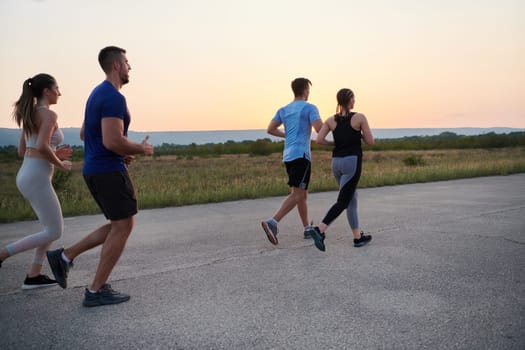 A diverse group of runners finds motivation and inspiration in each other as they train together for an upcoming competition, set against a breathtaking sunset backdrop.