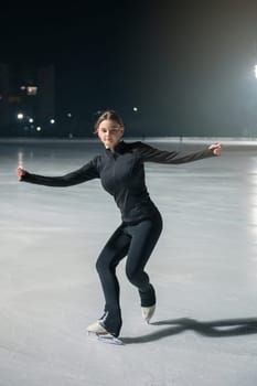 Beautiful young woman ice skating at city ice arena. Winter activities concept