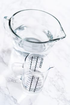 Glass measuring cups are filled with water, lined up and ready to be used in the careful washing of fresh strawberries, ensuring precise and thorough cleaning.