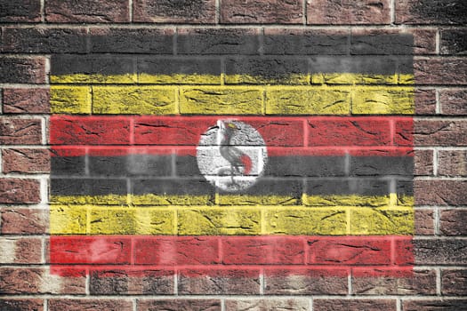 A Uganda flag on a brick wall background