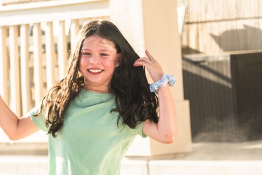 A joyful young girl gleefully gets soaked in refreshing water mist during a hot summer day.