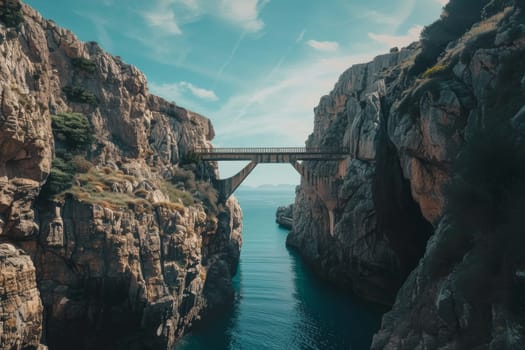 A sturdy bridge arches gracefully between towering cliffs above a serene blue inlet, with a clear sky extending into the horizon.