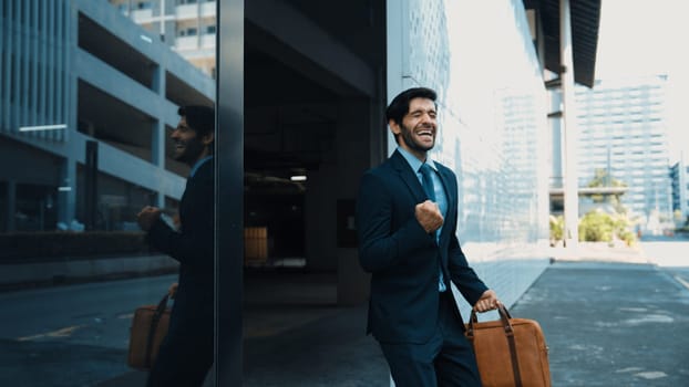 Skilled smart business man dancing with joyful while walking in glass wall. Project manger receive a good news, getting promotion, getting a successful job while express feeling of overjoy. Exultant.