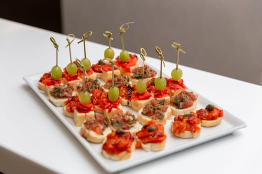 Plate with various seafood and meat canapes. Canape on white ceramic tray, pasty, bakery, fresh. Catering concept.