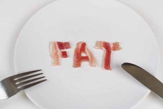 A plate with the word fat on it, accompanied by a fork and knife, symbolizing unhealthy eating habits.