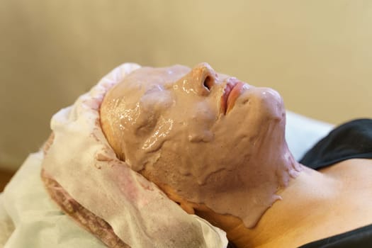 A woman having a facial mask applied during a skincare treatment at a beauty salon.