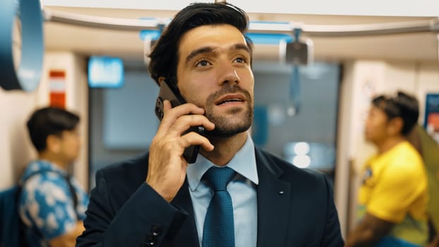 Smart business man phone calling to project manager while standing in train. Professional male leader talking to investor about marketing plan by using phone with blurring background. Exultant.