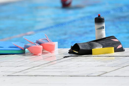 Fins and a bottle of water near the swimming pool